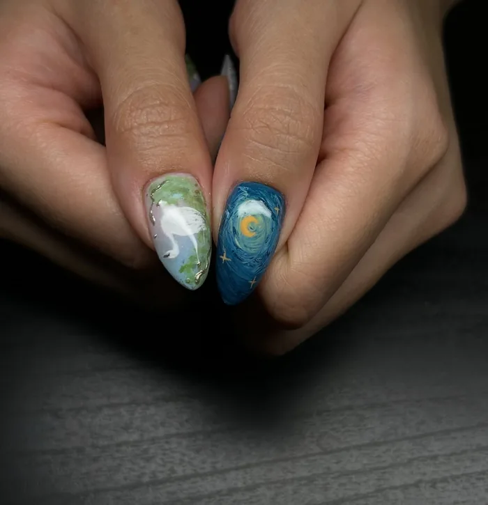 A white heron on soft green beside a Starry Night nail with a gold moon, both painted by hand